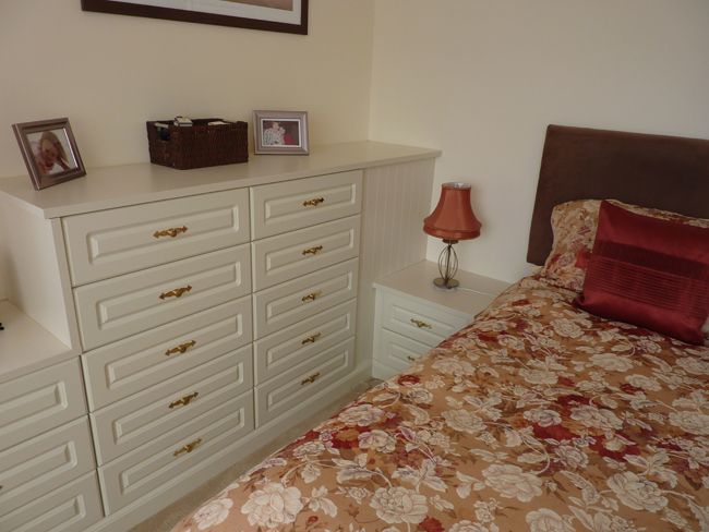 White cupboard and orange bed sheets