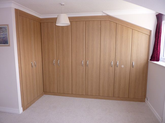 Oak wardrobes in L shape with one side slanted to match ceiling